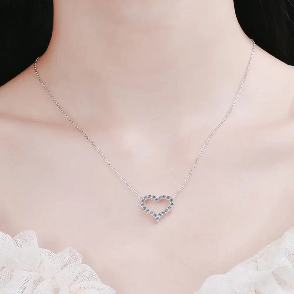 Moissanite heart pendant necklace on a model, showcasing sparkling stones and sterling silver design.